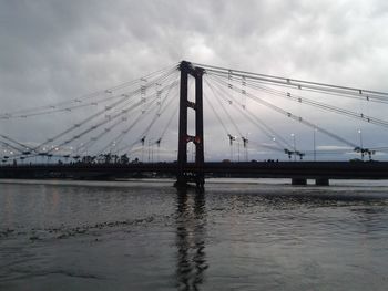 Bridge over river against cloudy sky