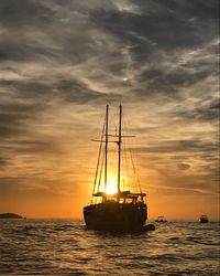 Silhouette ship in sea against sky during sunset