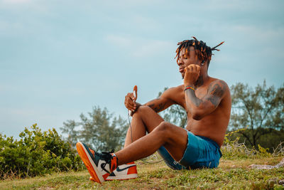 Man sitting on field against sky