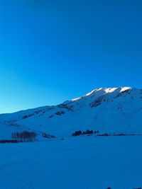 Scenic view of snowcapped mountains against clear blue sky