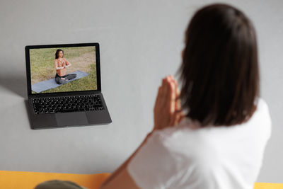 Rear view of woman using laptop on table