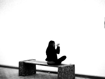 Full length of woman sitting on bench