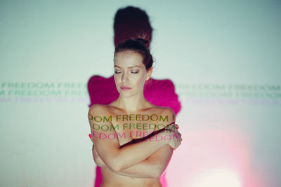 Portrait of young woman standing against wall