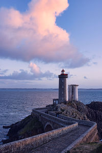 Lighthouse by sea against sky