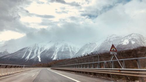 Road by snowcapped mountain against sky