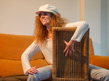 Mature smiling woman wearing cap sitting on chair at home