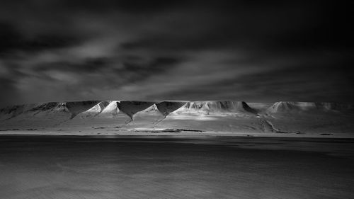 Snow covered mountains against cloudy sky