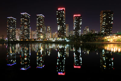 Illuminated buildings by river at night