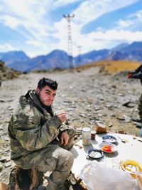 Portrait of young man sitting on snow covered land