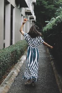 Rear view of woman dancing on footpath in park