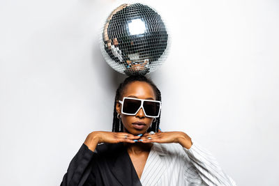 Portrait of young woman wearing sunglasses against white background