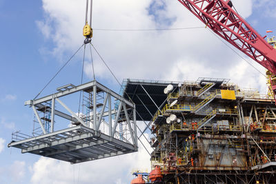 Low angle view of cranes against sky
