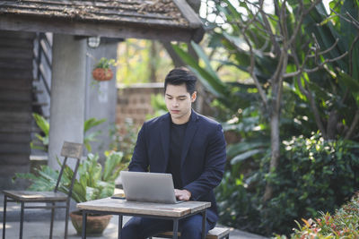 Young man using mobile phone while sitting on table