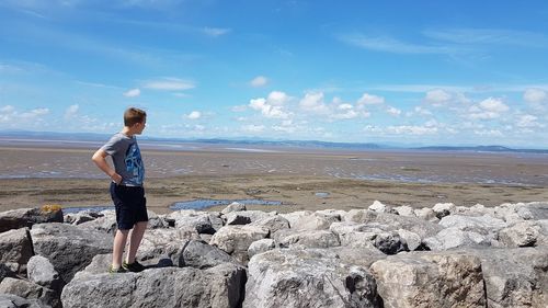 Full length of man standing on rock at beach against sky