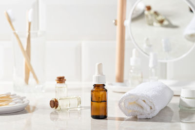 Massage oil or facial serum in a glass bottle in the bathroom. white towel, cream, toothbrushes