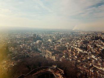 High angle view of city buildings against cloudy sky