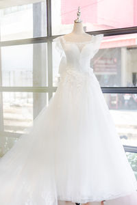 Midsection of woman wearing mask against white window