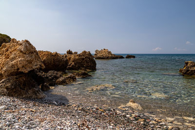 Rocks on sea shore against sky