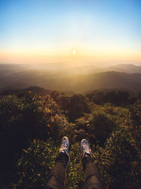 Low section of person against sky during sunset