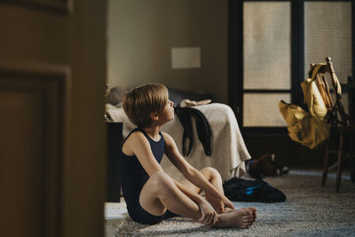 Boy day dreaming while sitting on carpet in bedroom at home