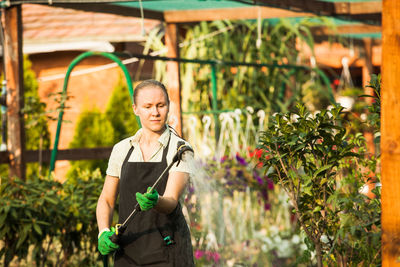 Full length of senior woman standing in greenhouse