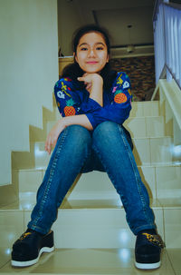 Portrait of a smiling young woman sitting on floor