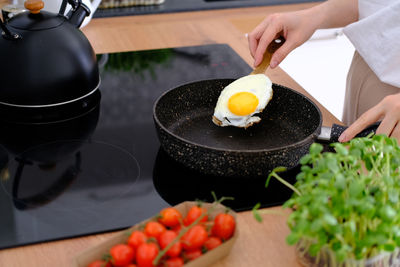 Woman frying scrambled eggs in a frying pan on a kitchen stove