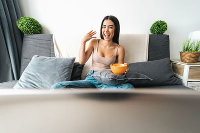 Mid adult woman sitting on sofa at home