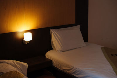 Close-up of electric lamp on bed against wall at home
