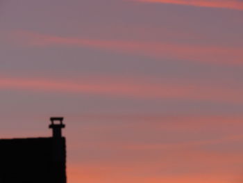 Low angle view of silhouette building against orange sky