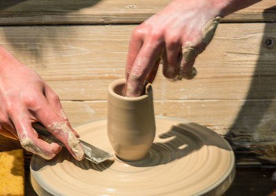 Cropped hands of man making pot in workshop