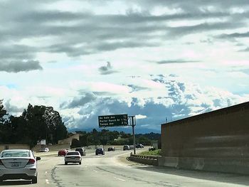 Cars on road in city against storm clouds