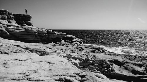 Rocky sea shore against clear sky