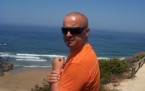 Portrait of man wearing sunglasses standing at beach against clear sky