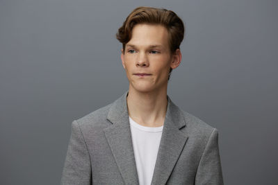 Portrait of young man standing against gray background