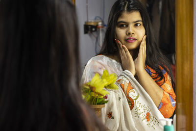 A beautiful indian woman in white saree looking herself in mirror with smiling face