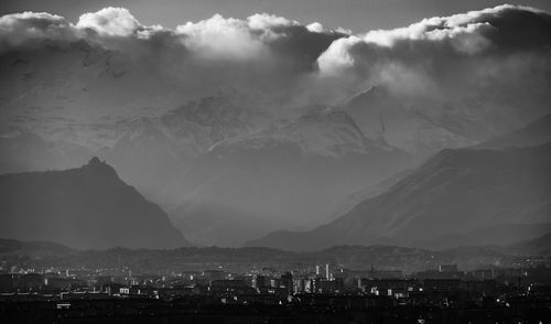 Cityscape by mountains against sky at night