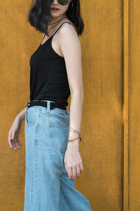 Side view of beautiful woman standing against wall