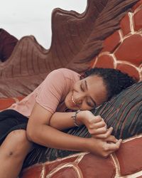 Smiling young woman lying on built structure outdoors