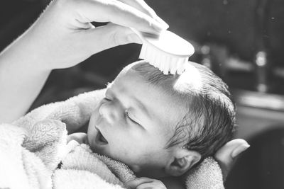 Cropped image of mother combing baby hair at home