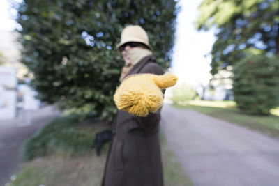Woman with hat and sunglasses showing yellow gloves