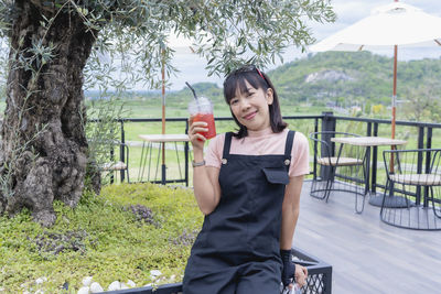 Happy asian woman smiling and showing ice berry juice in a plastic cup refreshing drinks for summer