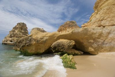 Rock formation on beach against sky