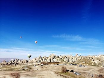 Hot air balloons flying over land against blue sky