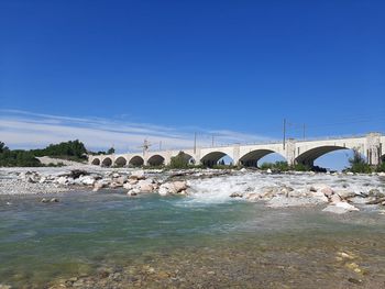 Bridge over river against clear blue sky