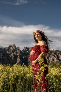 Portrait of a pregnant woman in a red dress touching her tummy