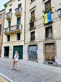 Rear view of woman walking on street and ukrainian flag on window 