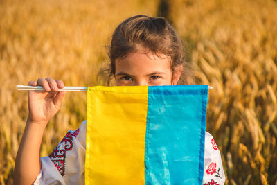 Girl covering face with ukrainian flag