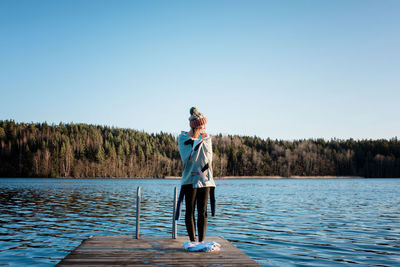 Woman standing on the end of a pier wrapped in a towel after ice swim