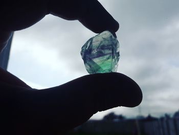 Close-up of hand holding glass against sky